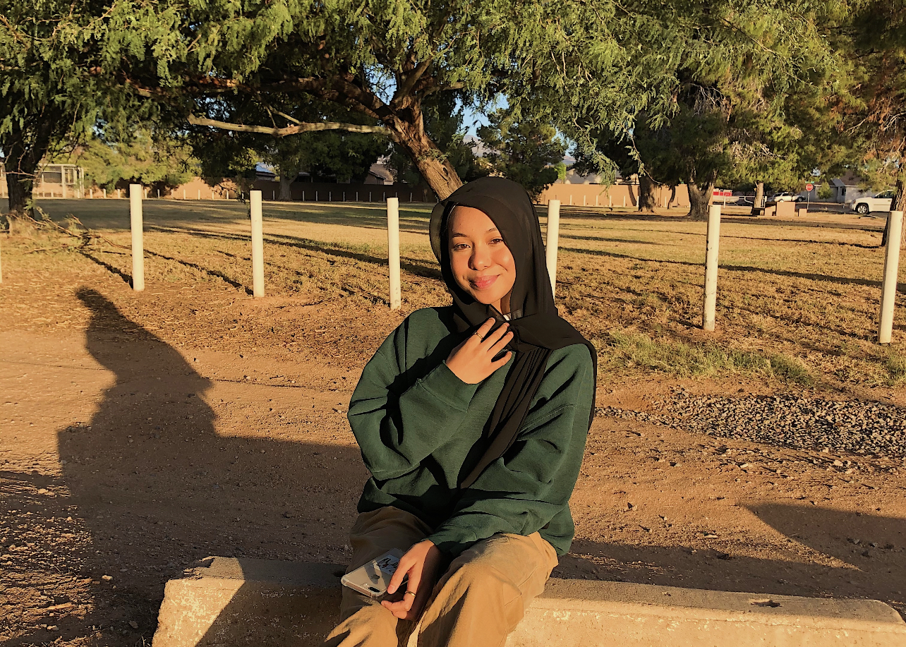 Aida Zaki sits on a bench and smiles at the camera