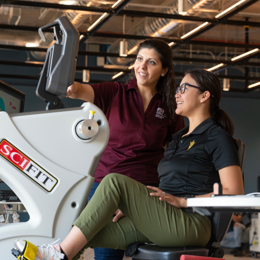Woman helping another woman on a workout bike