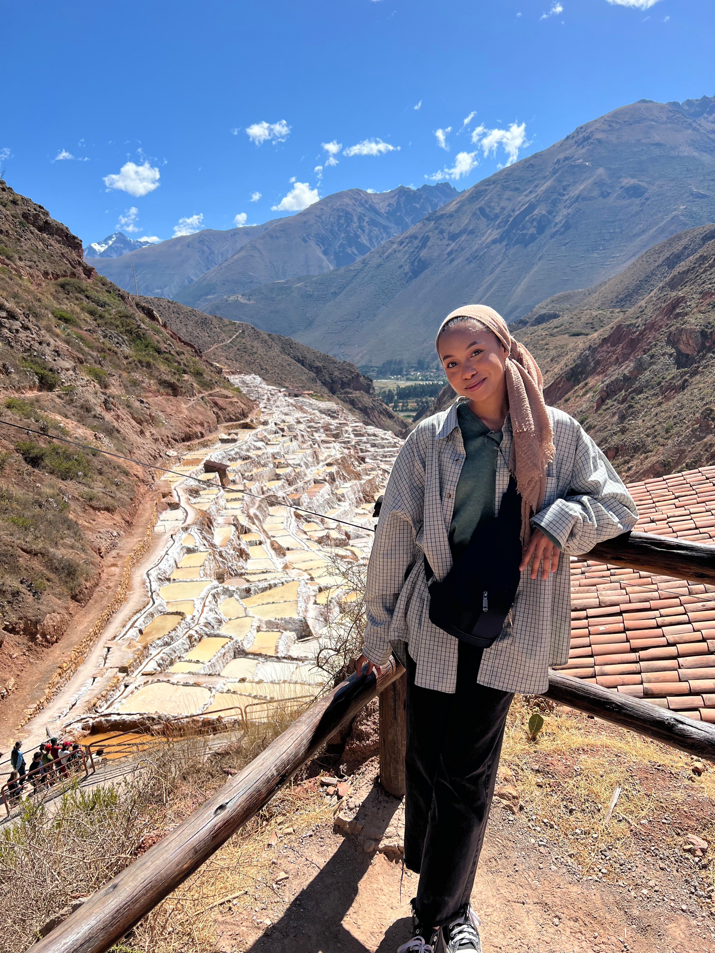 Aida Zaki leans against a railing with a view of salt mines in the background