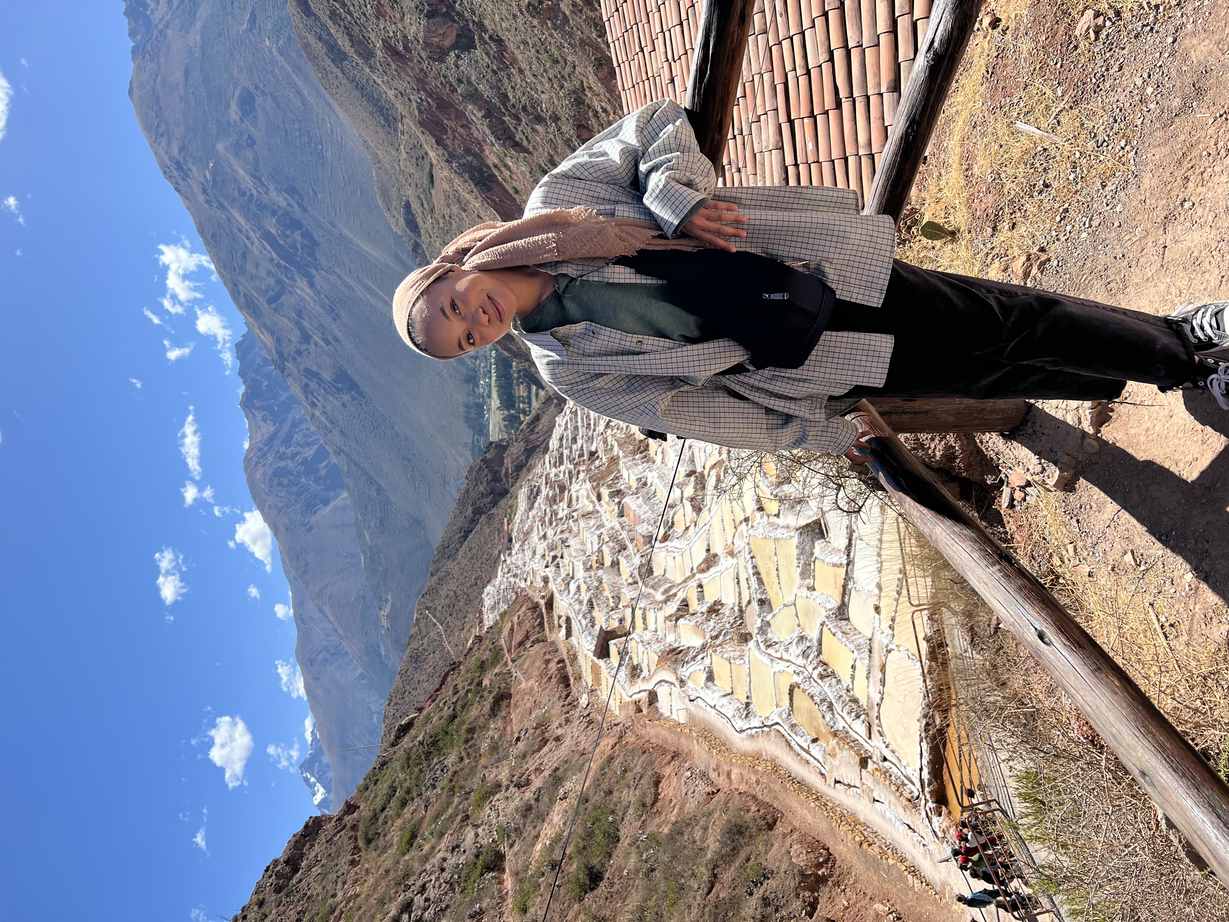 Aida Zaki leans against a railing with a view of salt mines in the background