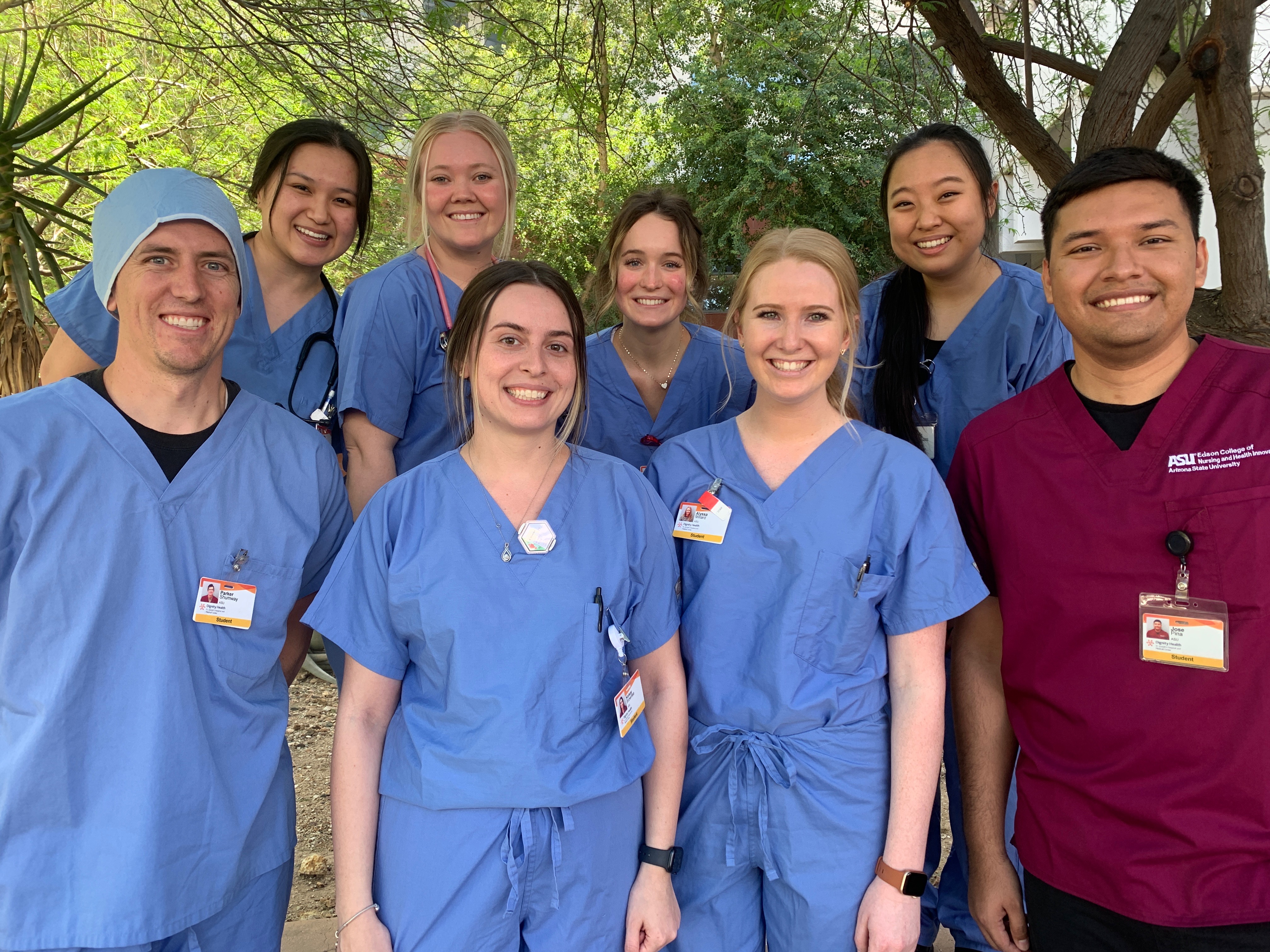 Edson College nursing students pose outside of their clinical home in blue scrubs