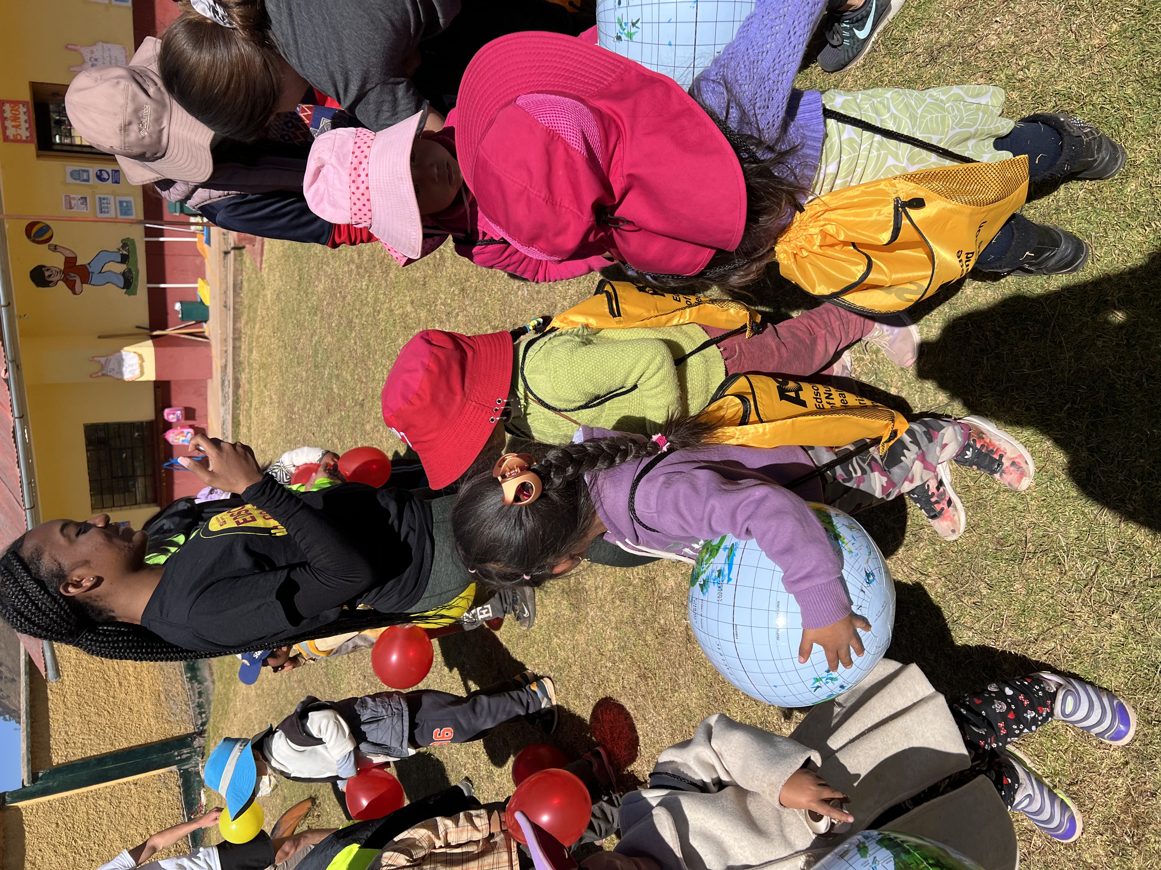 Shaniece Randolph looks on as little kids play with red balloons