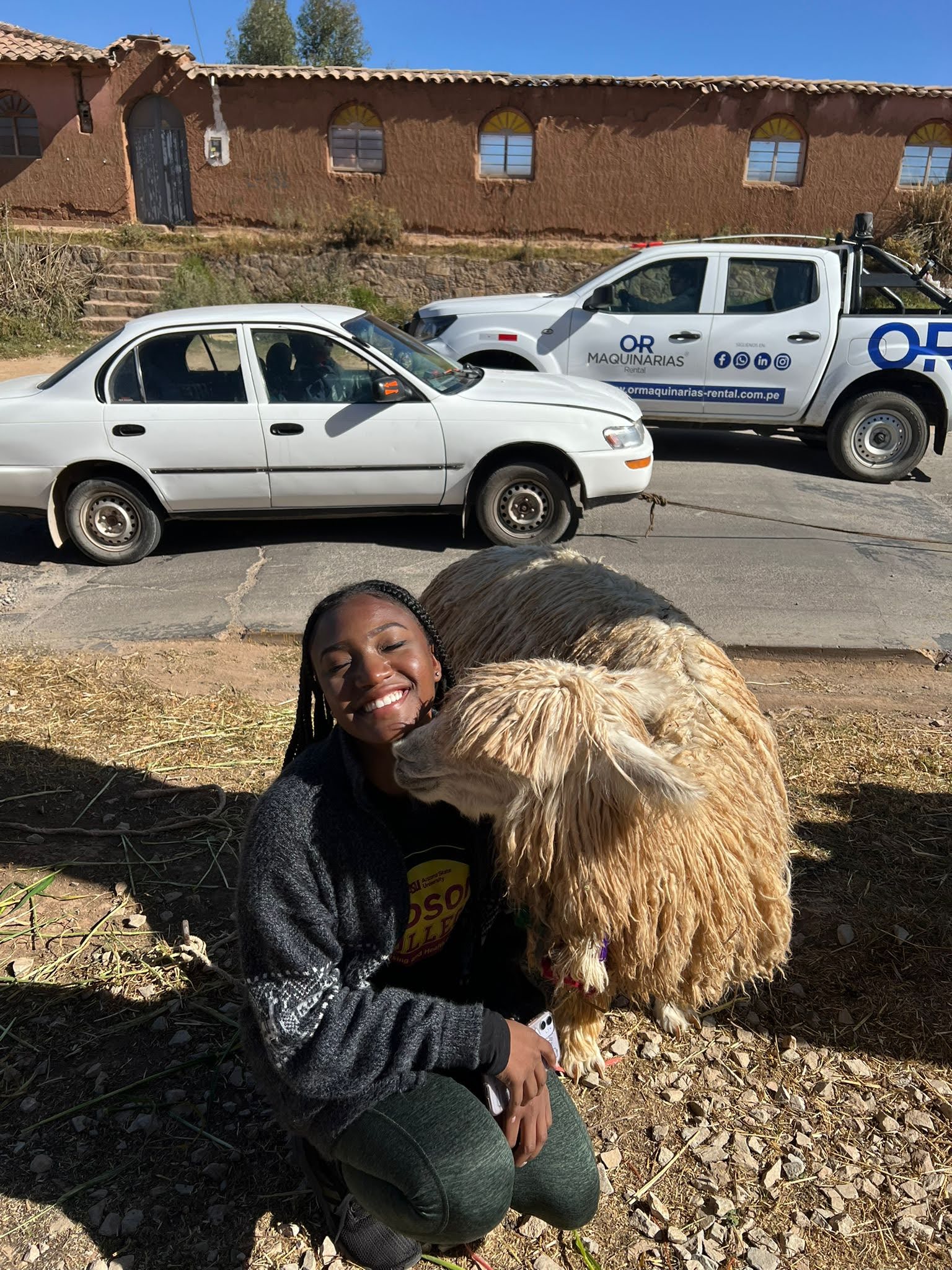 Shaniece Randolph smiles at the camera standing next to a wooly lamb.