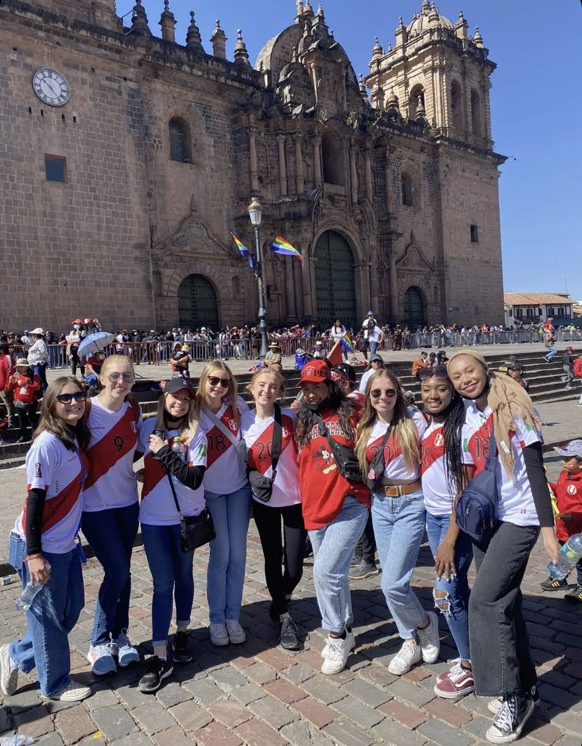 Edson College students pose in white and red jerseys in a Peruvian Plaza