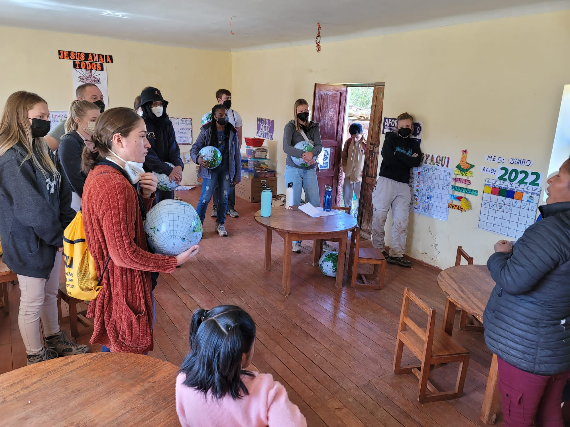 ASU students stand inside a classroom outside of Cusco, Peru with local school children