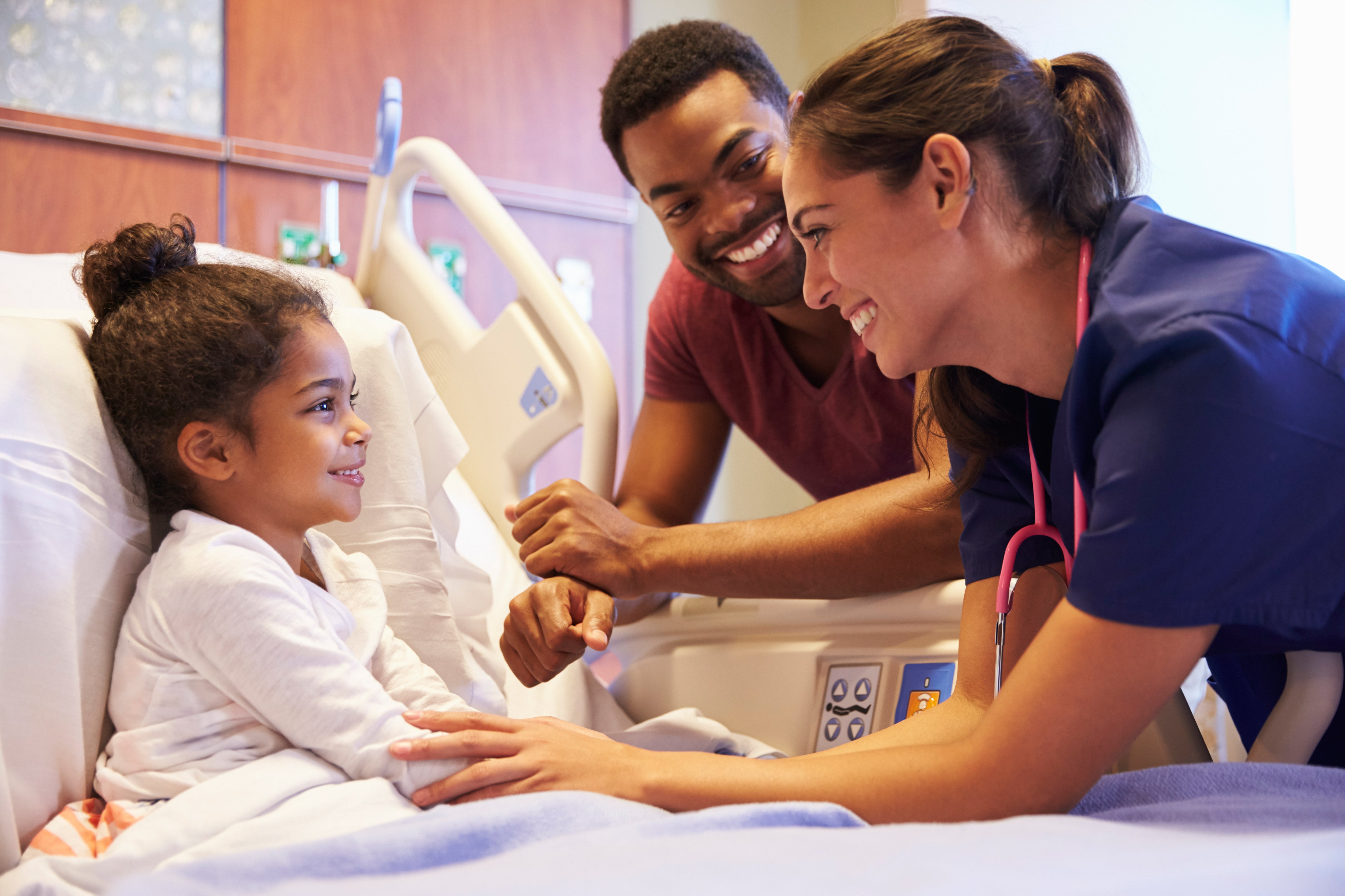 Nurses, with a child patient in bed