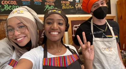 Students pose in aprons and chefs hats inside of a kitchen
