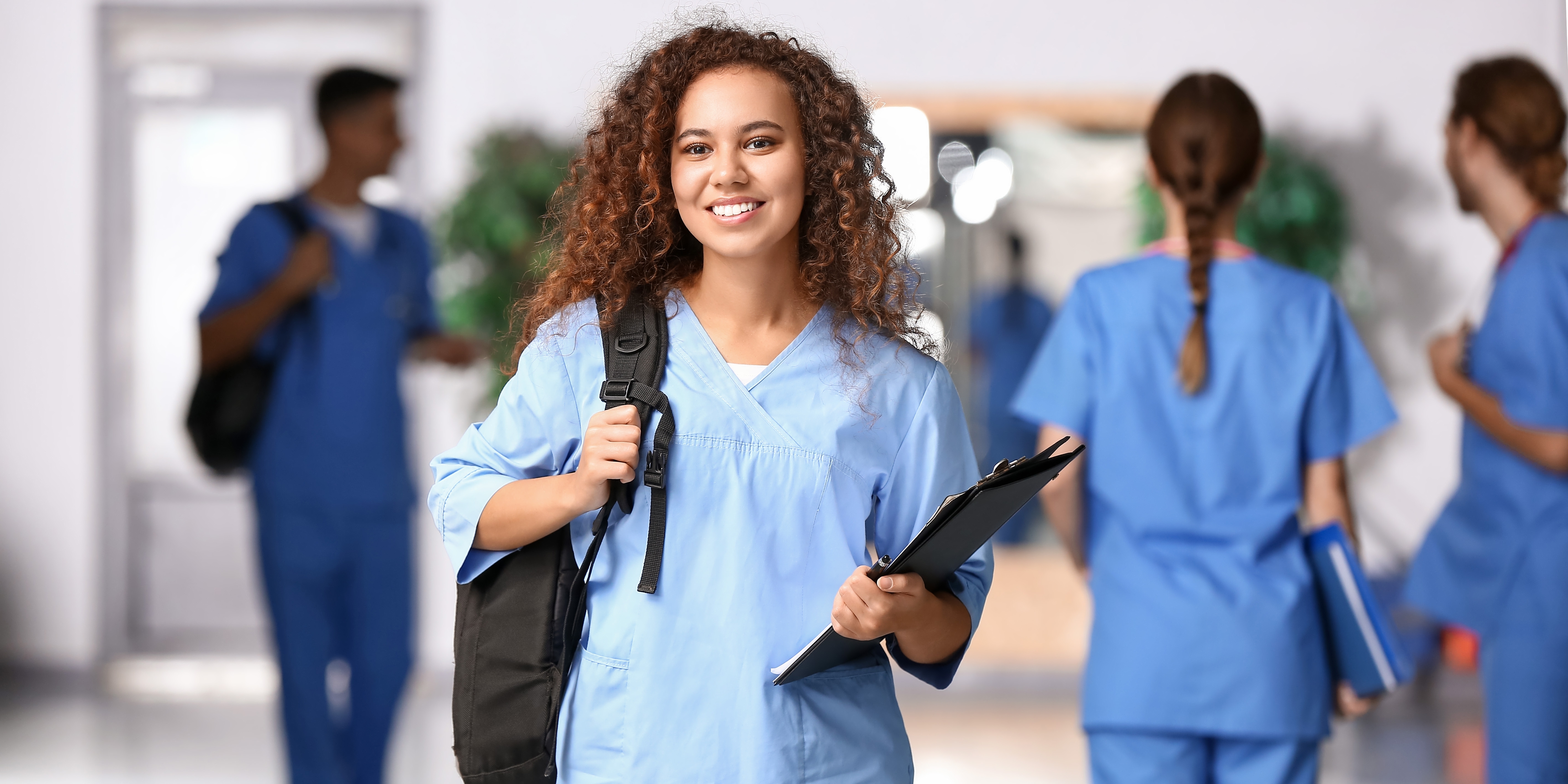Nurse in blue scrubs and backpack